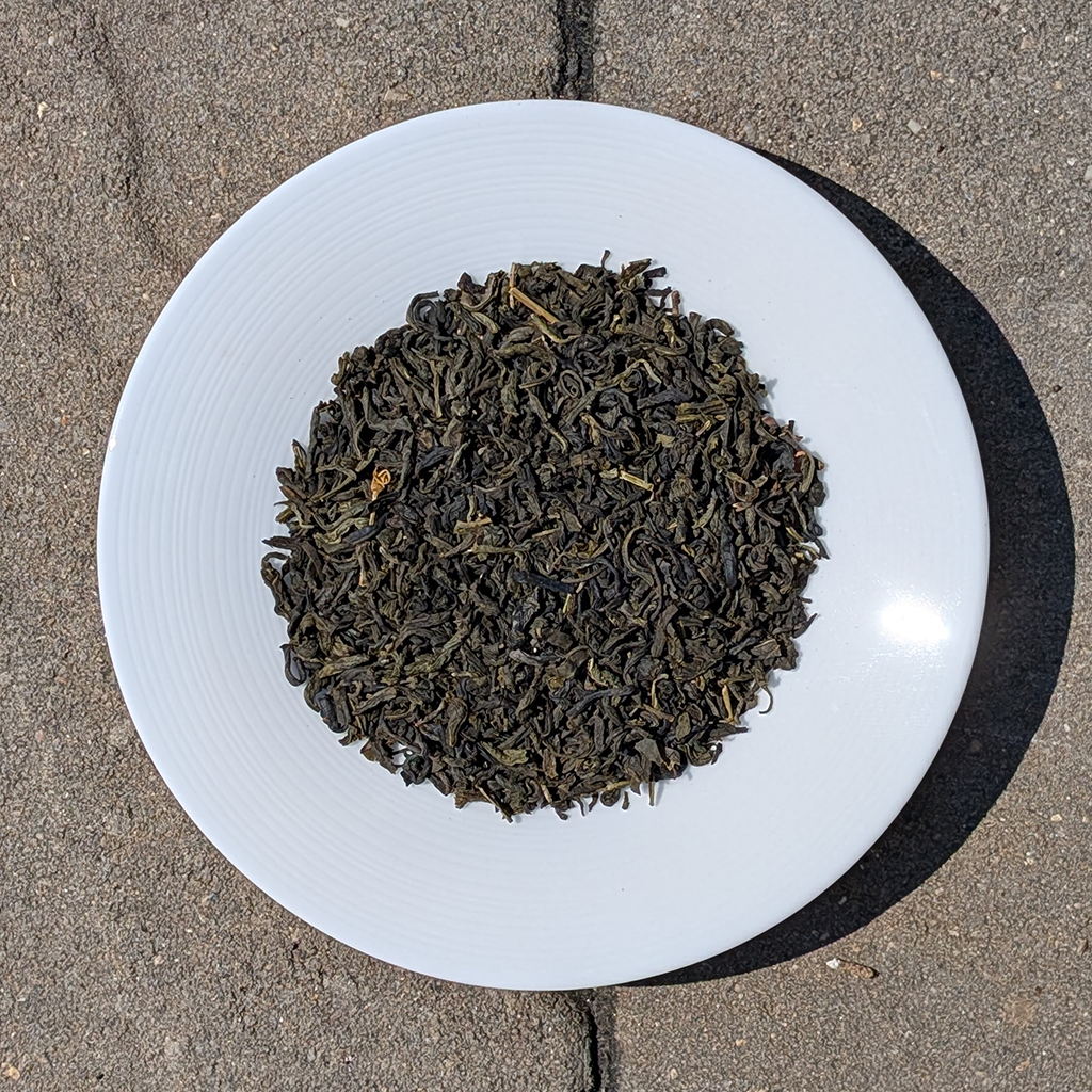 Dry black tea leaves on a white plate with a concrete background