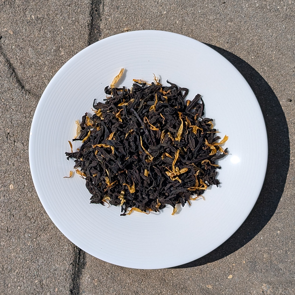 White plate with black tea leaves on a concrete surface