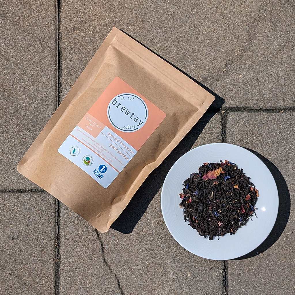 Tea package with a label and a bowl of tea leaves on a stone surface