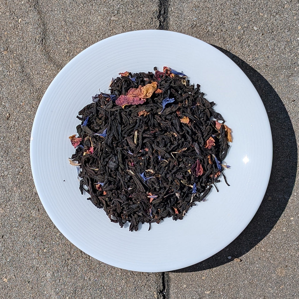 Assorted dried tea leaves on a white plate with a concrete floor background